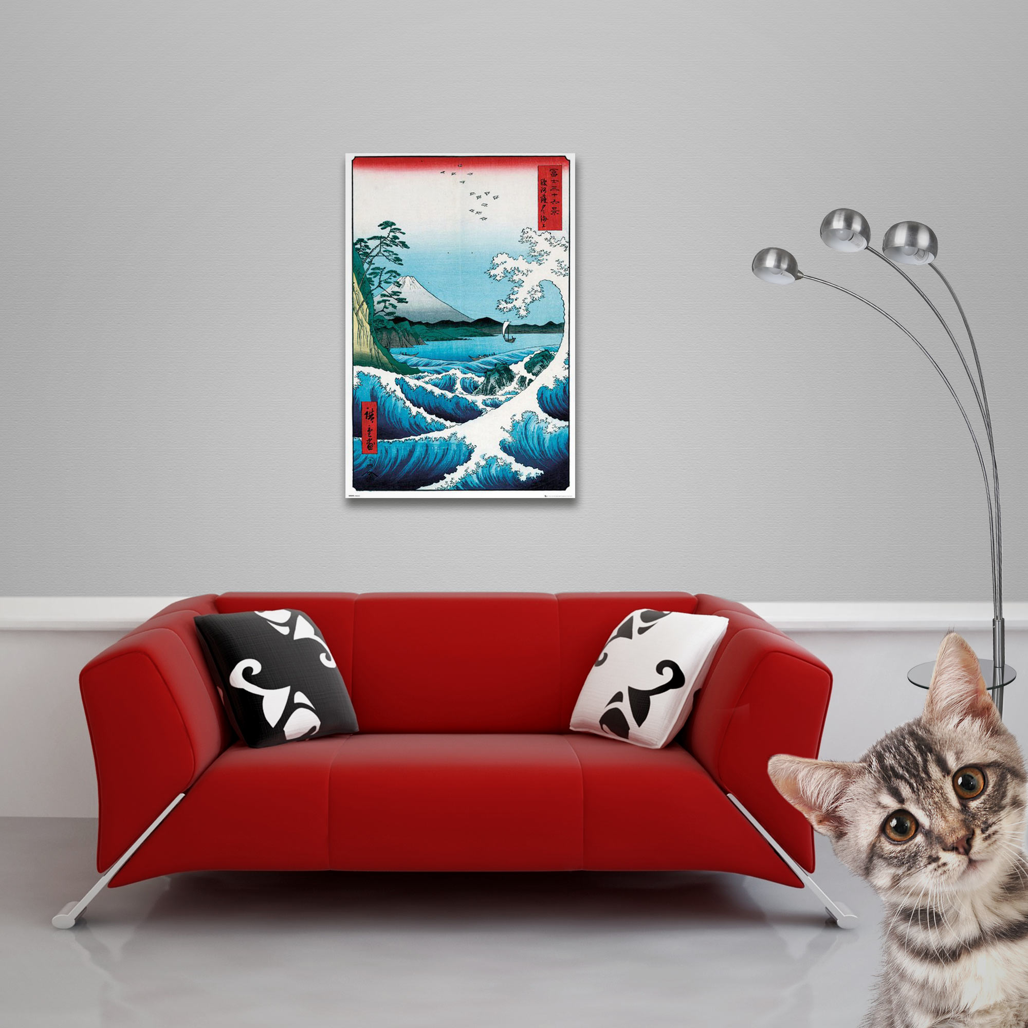 Ein rotes Sofa mit Kissen, ein Bild von Wellen und eine Katze, die in die Kamera schaut.