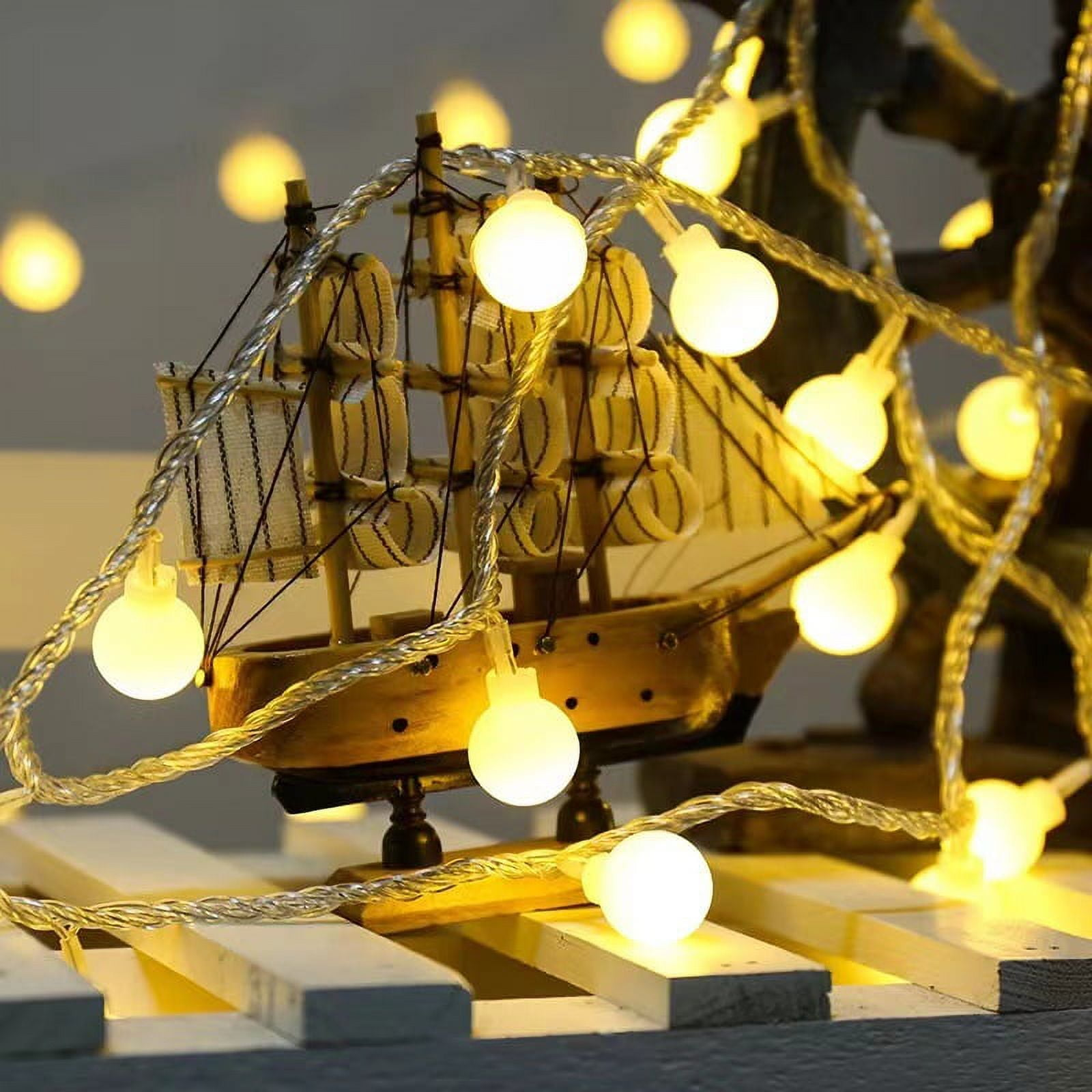 Ein kleines Holzsegelschiff mit Lichtern. Die Lichter sind rund und gelb.