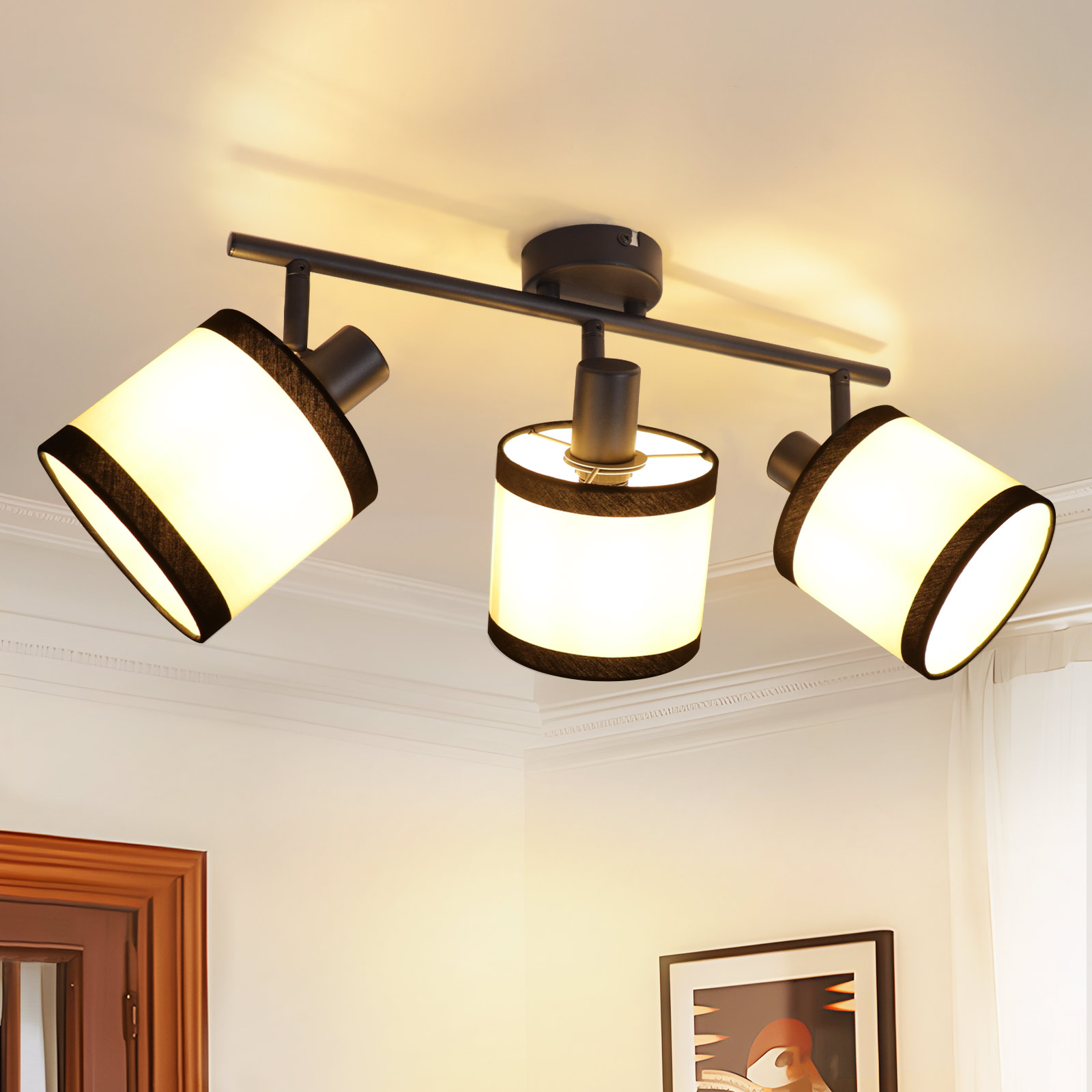 Deckenleuchte mit drei verstellbaren Lampen. Schwarzer Rahmen, weiße und schwarze Schirme, an weißer Decke montiert.