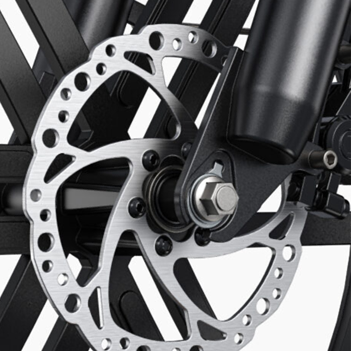 Zbliżenie hamulca tarczowego roweru. Srebrzysta tarcza z otworami, zamontowana na czarnym widelcu. Struktura koła widoczna w tle.