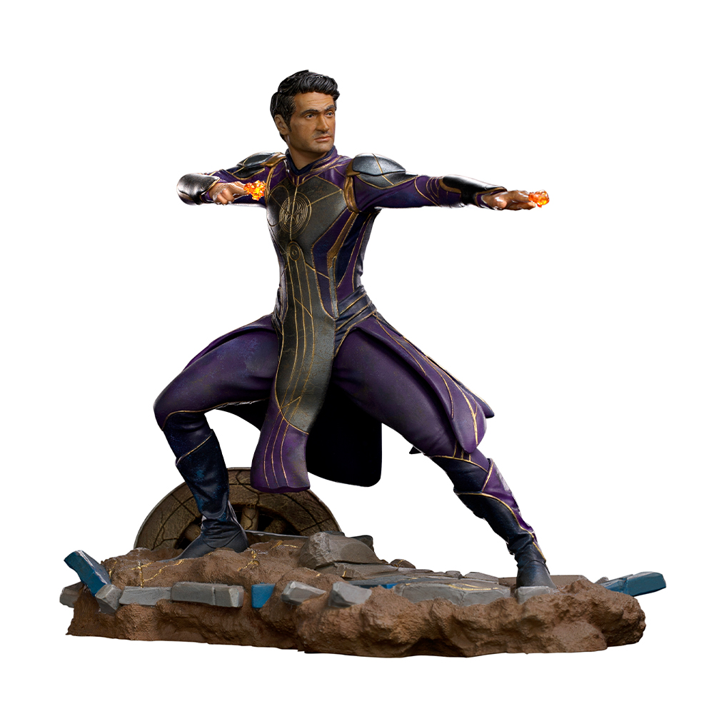 Statua di un uomo in costume viola e oro, braccia tese, che tiene globi luminosi. Si trova su una base rocciosa.