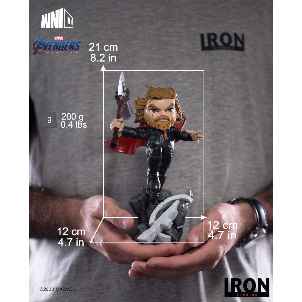 Una persona tiene una statuetta di Thor. È una piccola statua di Thor con un martello. Lo sfondo è una camicia grigia.