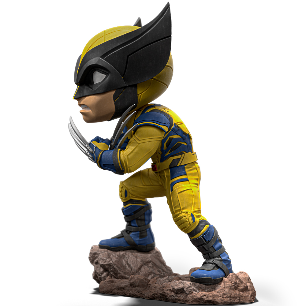 Statuetta di Wolverine in tuta gialla e blu, maschera nera, artigli estesi, in piedi su roccia, sfondo bianco.