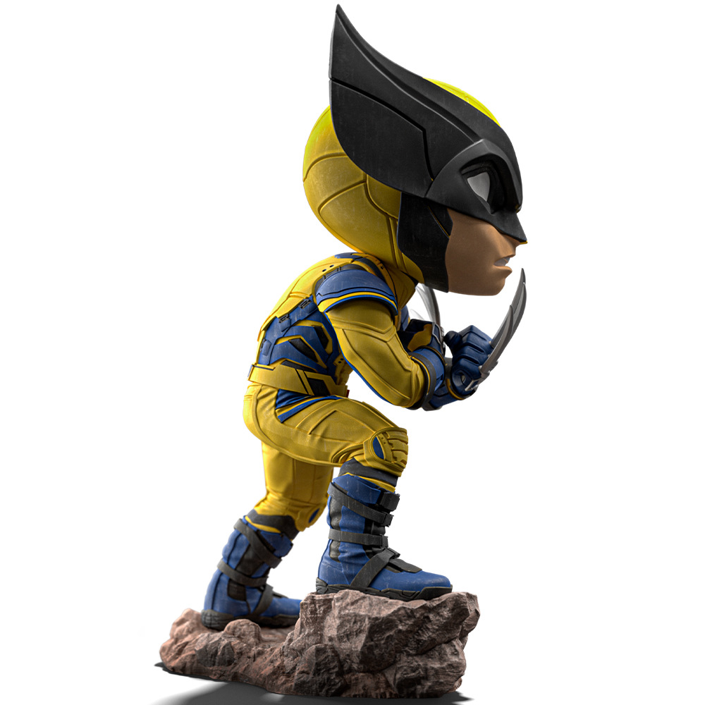Una statuetta di Wolverine in tuta gialla e blu, maschera nera e artigli, in piedi su una roccia su sfondo bianco.