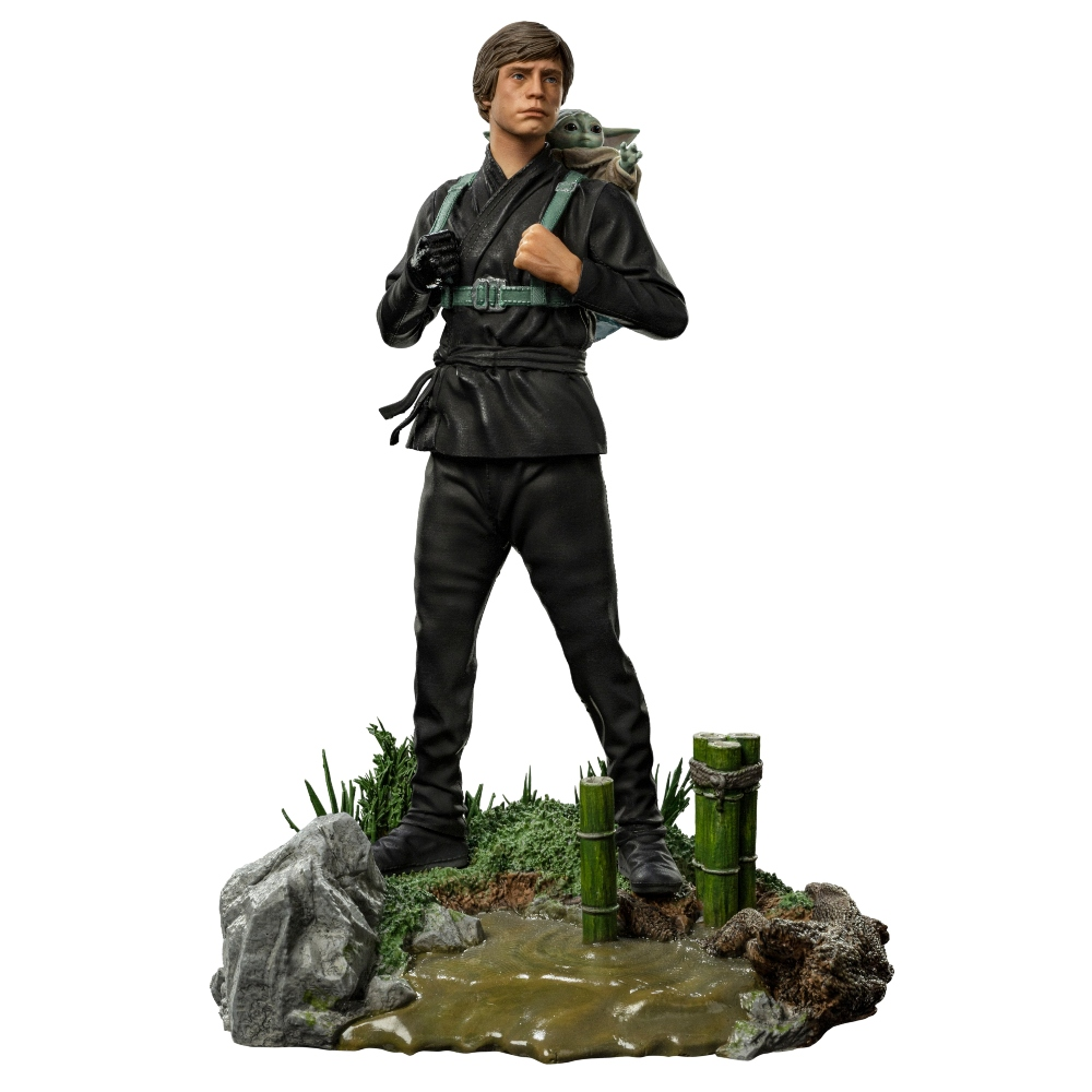 Eine Figur von Luke Skywalker in schwarzem Outfit mit Grogu auf dem Rücken, die auf einer Basis mit Wasser, Felsen und Bambus steht.