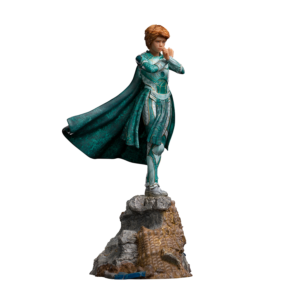Una statuetta di una persona con armatura e mantello color verde acqua, in piedi su una roccia. La persona ha i capelli rossi corti ed è in posizione di combattimento.