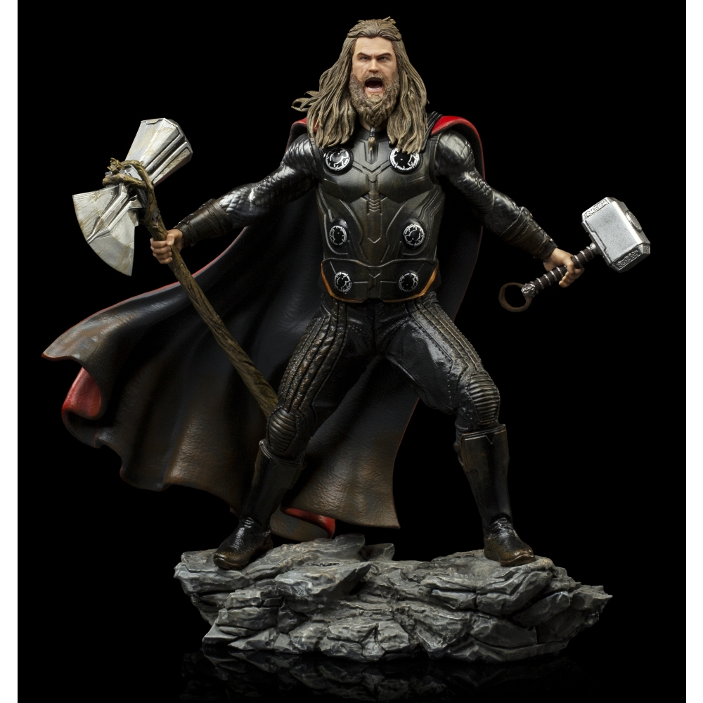 Statua di Thor con capelli lunghi, barba e armatura, che tiene un martello e un'ascia, in piedi sulle rocce, sfondo nero.
