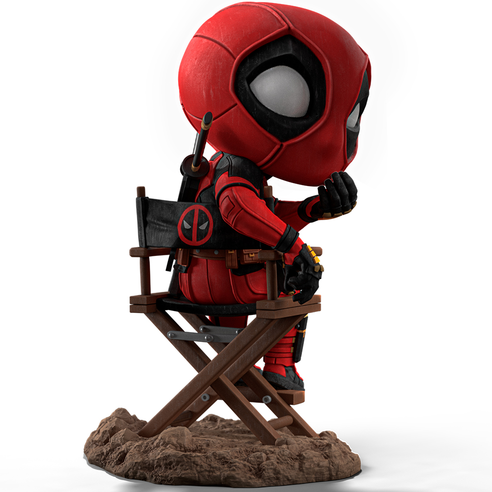 Figura di Deadpool seduta su una sedia da regista su una base marrone. Indossa un abito rosso e nero e ha una spada sulla schiena.