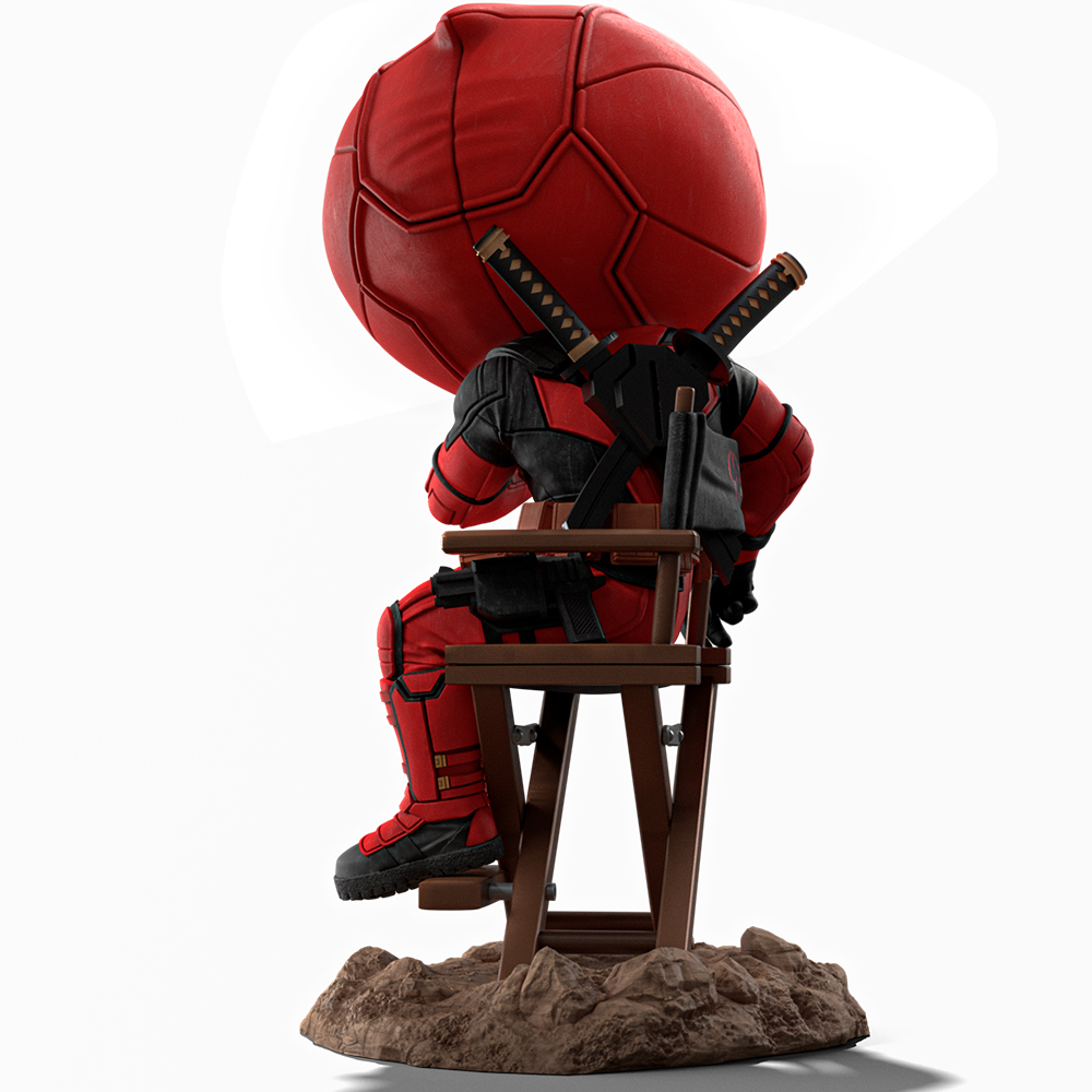Figura di Deadpool seduta su una sedia di legno, con una grande testa a forma di pallone da calcio rosso. Ha delle spade sulla schiena. La base è un tumulo marrone.