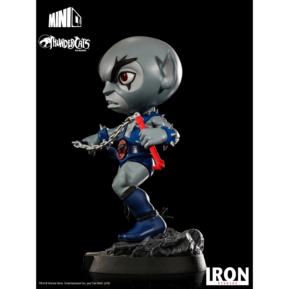 Una figura dei Thundercats è in piedi con una catena e un'arma rossa. Ha una testa grigia, un completo blu ed è su una base di roccia, con il logo visibile.