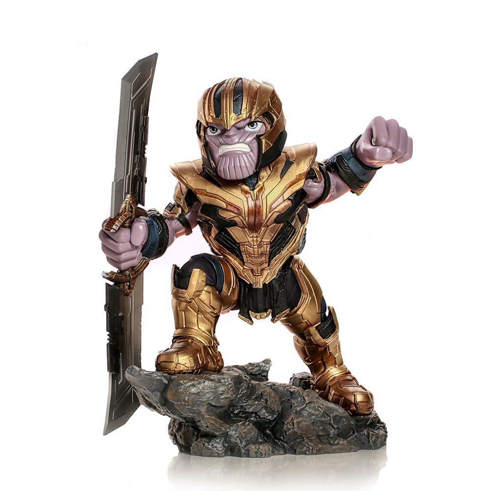 Una statuetta di Thanos con armatura e casco dorati, che tiene una spada, in posa su una roccia, con sfondo bianco.