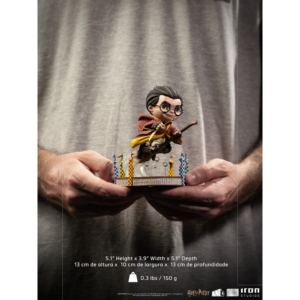 Una persona tiene in mano una statuina di Harry Potter. La statuina mostra Harry su una scopa, con un boccino d'oro, davanti ai pali della porta.