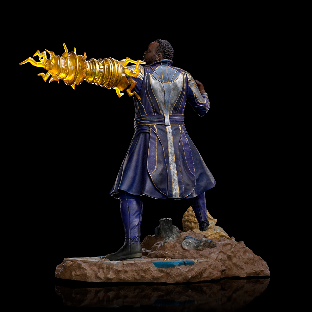 Figura di un uomo in costume blu e oro, con un'arma energetica dorata. Sfondo nero. In piedi su una base marrone.