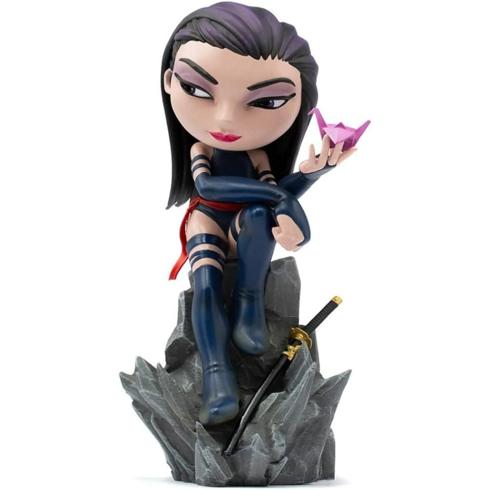 Una statuetta di una donna in abito blu con fascia rossa, che tiene una gru origami rosa, seduta su una roccia grigia con una spada.