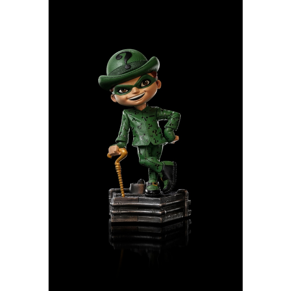 La statuetta dell'Enigmista è su una piattaforma. È verde con punti interrogativi e tiene un bastone. Visibili maschera e cappello verdi con punto interrogativo.