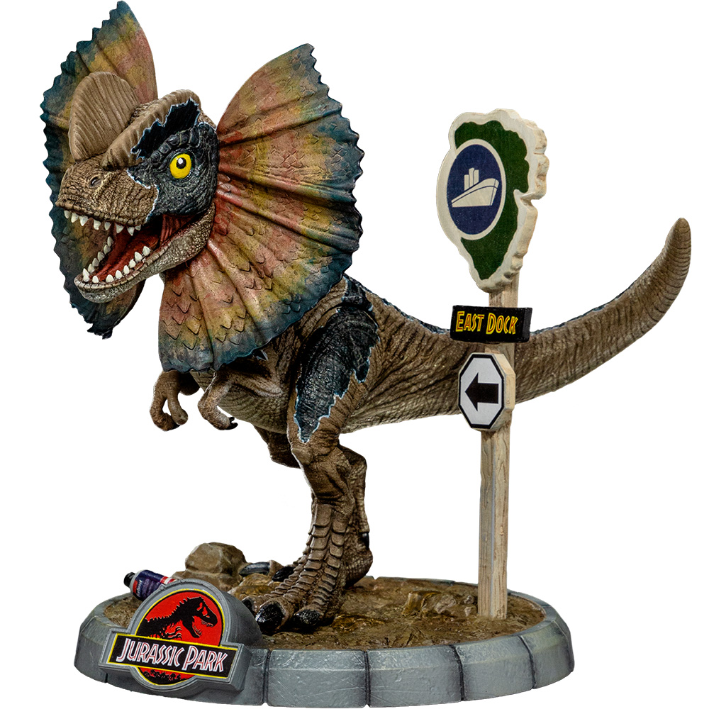 Una figura di Dilophosaurus di Jurassic Park. Ha un collare, la bocca aperta ed è accanto a un cartello con scritto 'East Dock'.