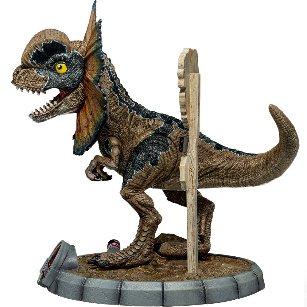 Una statuetta di dinosauro Dilophosaurus è in piedi su una base grigia. Ha segni marroni e neri, un collare e un cartello di legno.