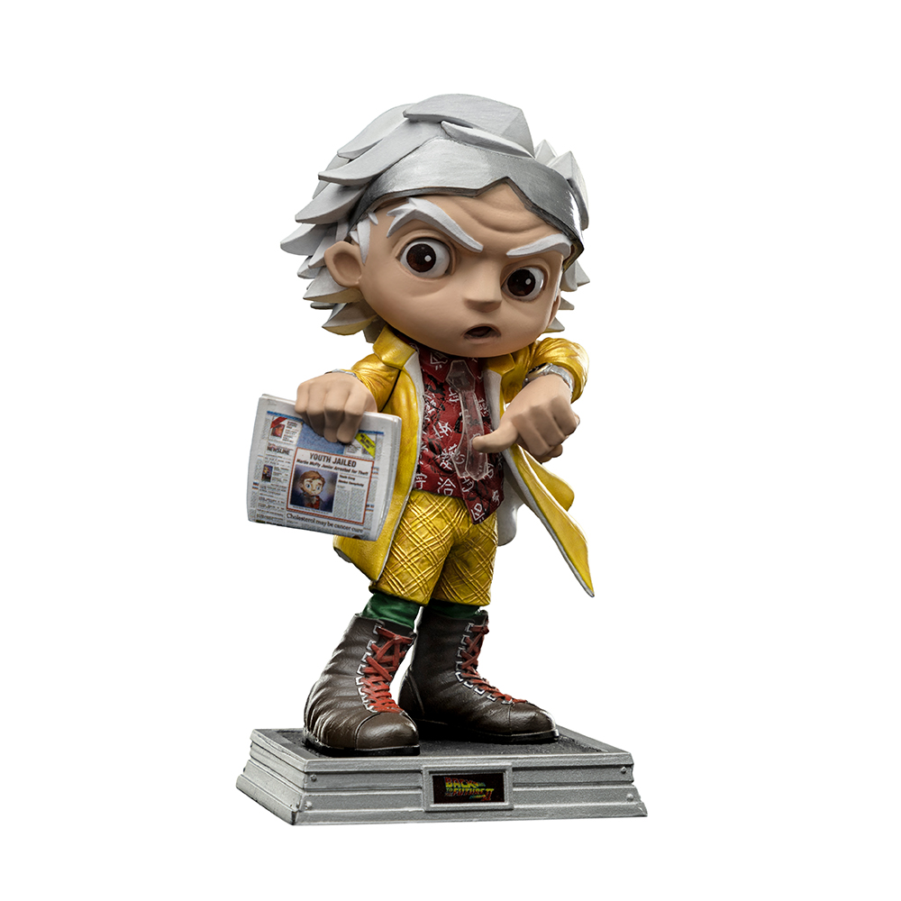 Una statuetta di Doc Brown di Ritorno al Futuro. Tiene in mano un giornale, indica e indossa un cappotto e stivali gialli.