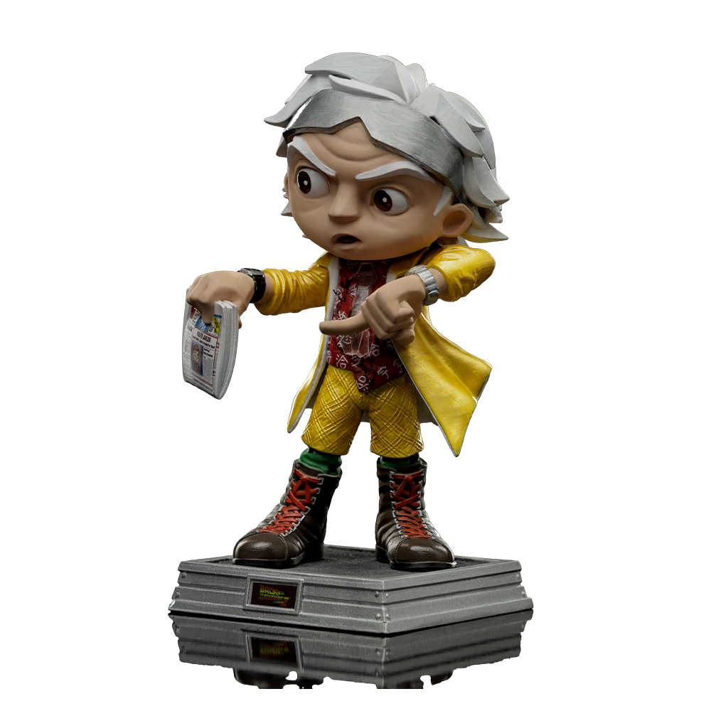 Una statuetta di Doc Brown di Ritorno al futuro, con cappotto giallo e pantaloni a quadri, indica, tiene un giornale, in piedi su una base.