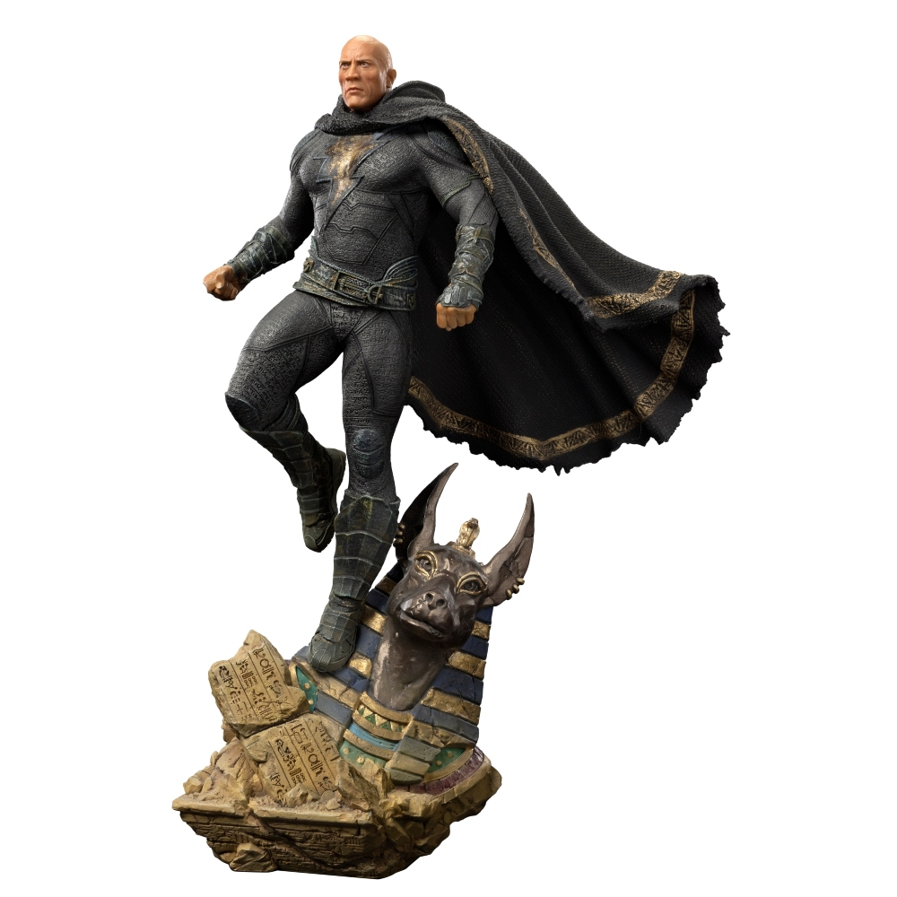 Una statuetta di Black Adam, un uomo calvo in abito nero e mantello, in piedi su una base con una testa di Anubi.