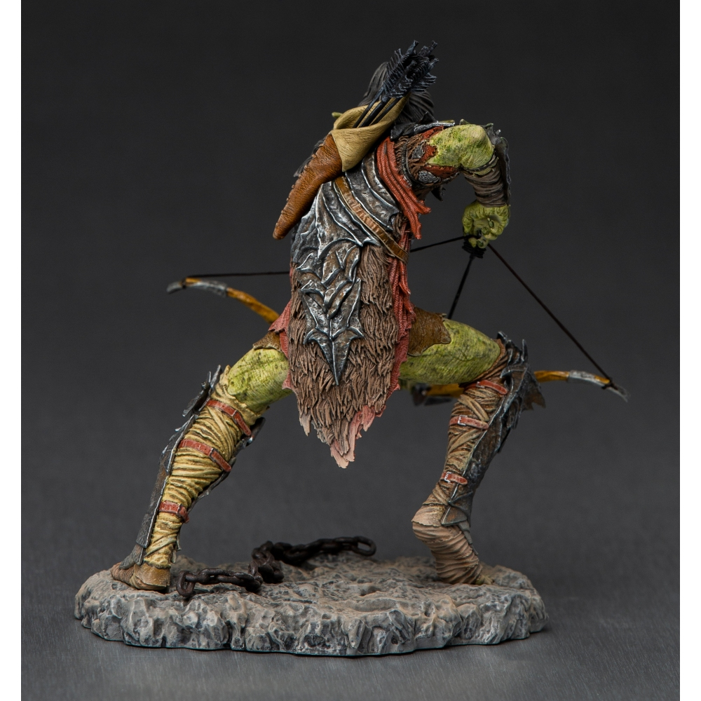 Una statuetta di un arciere orco, pelle verde, petto corazzato, che mira con un arco. Si trova su una base rocciosa con una catena, sfondo scuro.