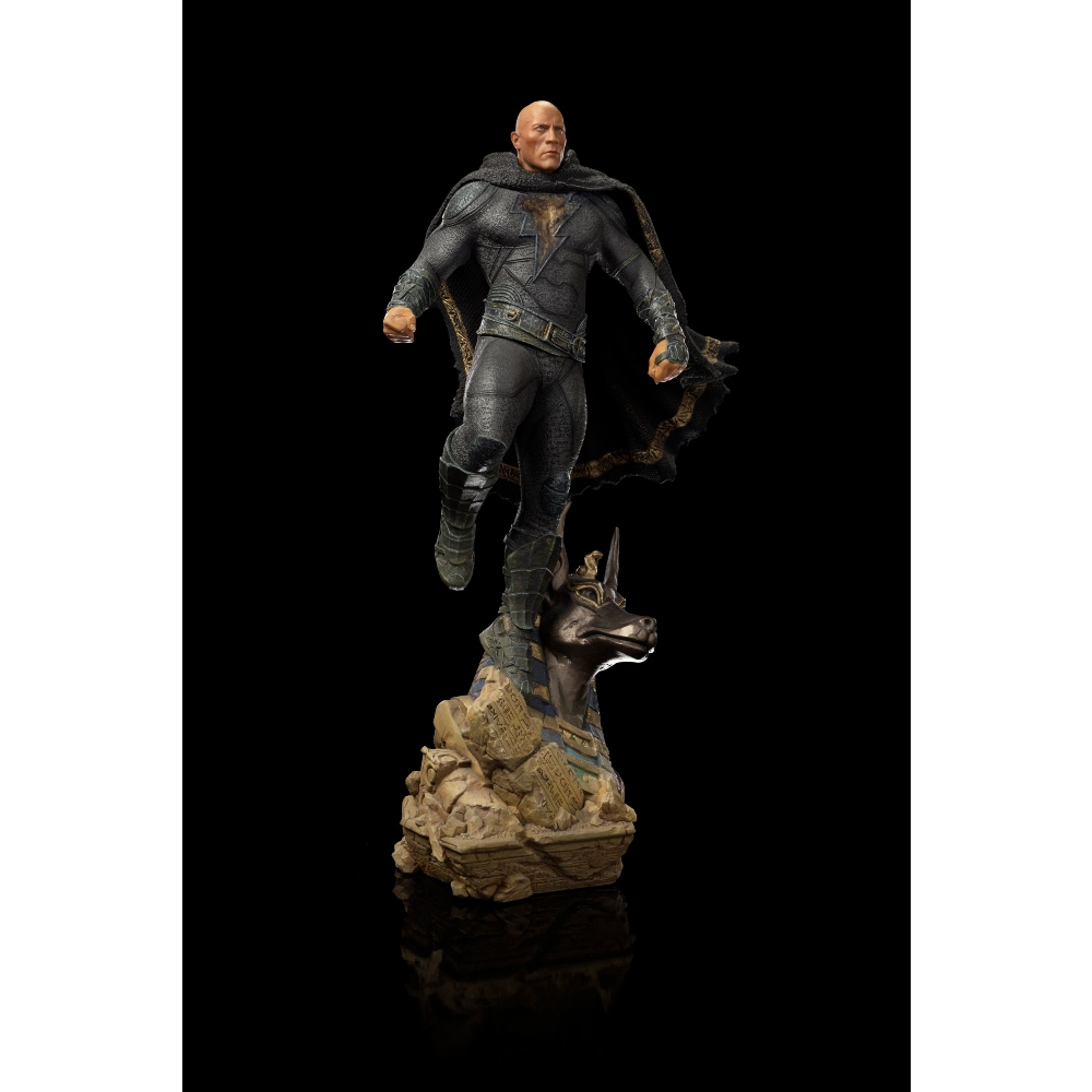 Una statua di Black Adam. È in piedi su una base con una testa di cane. Indossa un abito nero e un mantello. Lo sfondo è nero.
