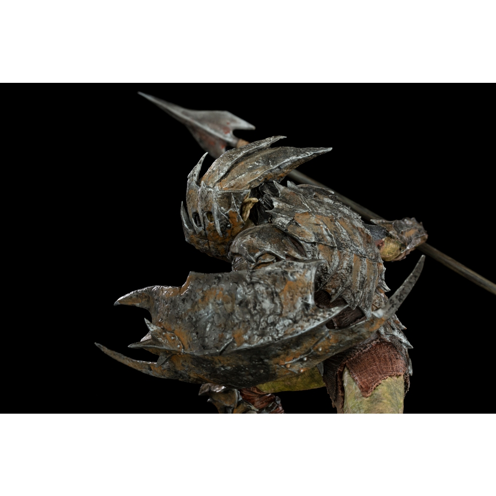 Una figura di orco con armatura, scudo e lancia. L'armatura è dettagliata e lo sfondo è nero. L'orco è in posizione difensiva.