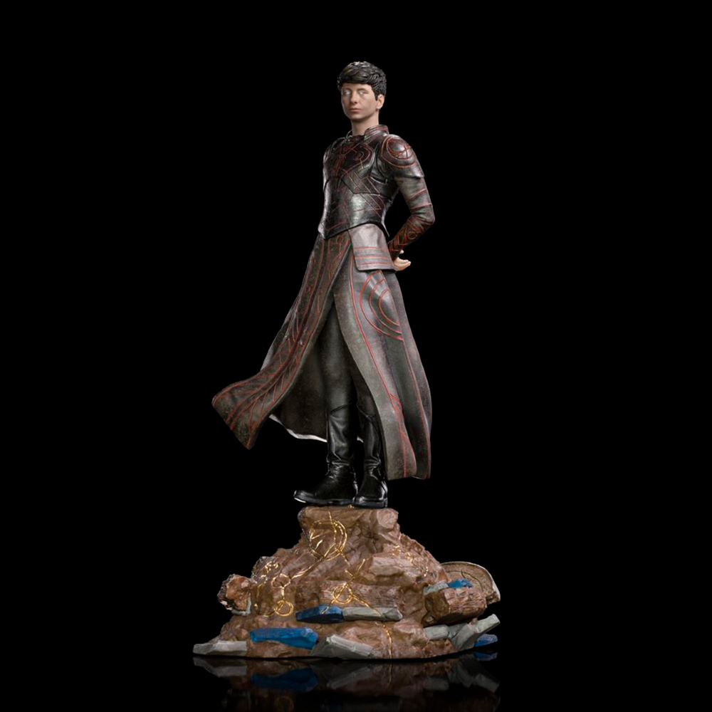 Una statua di un uomo con un cappotto lungo. Si trova su una base di roccia con dettagli dorati. Lo sfondo è nero.