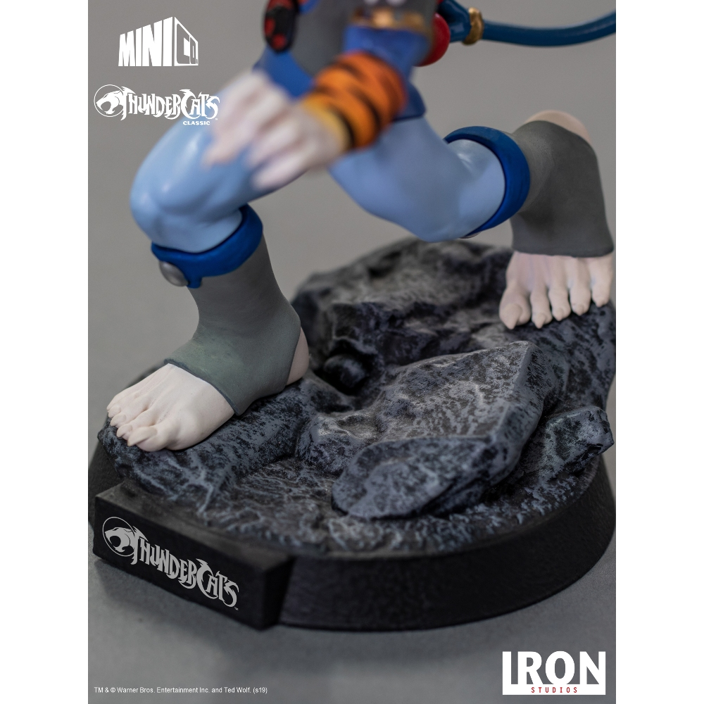 Una statuetta di Thundercats mostra i piedi di un personaggio su una base rocciosa. La figura ha pantaloni blu e protezioni per le caviglie grigie.