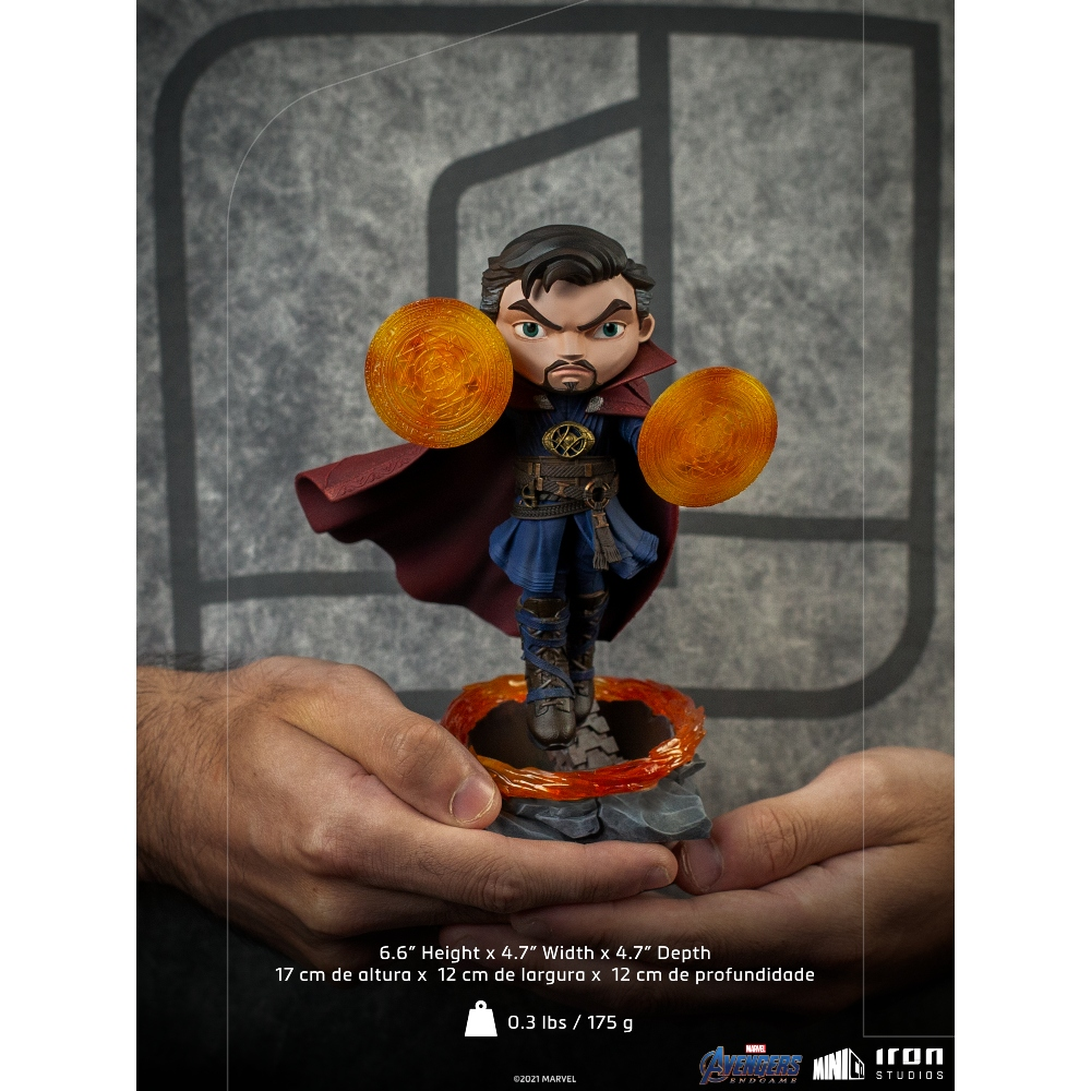 Statuina di Doctor Strange tenuta in mano. Indossa un completo blu e un mantello rosso. Due cerchi di energia arancione fluttuano vicino alle sue mani.