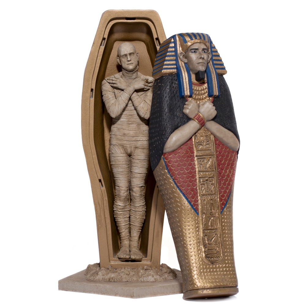 Una statua di mummia si trova in un sarcofago. Un'altra statua di mummia è fuori dal suo sarcofago, entrambe su sfondo bianco.