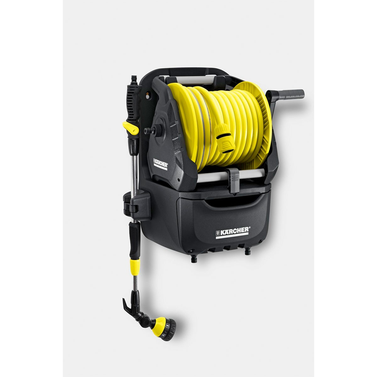 Una manguera amarilla enrollada en un carrete negro montado en la pared. Una boquilla y una manguera están unidas. La marca 'Karcher' es visible.