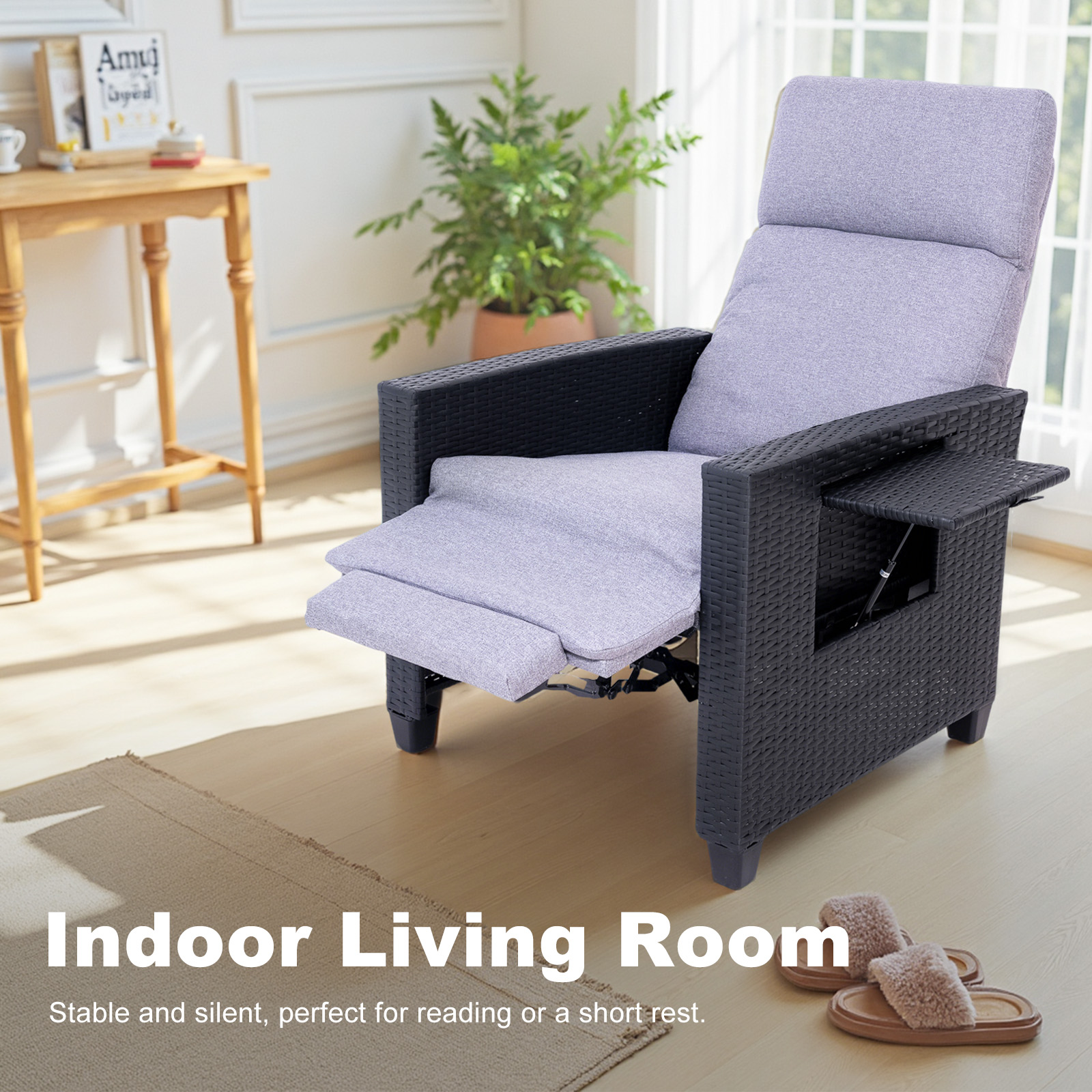 Un sillón reclinable de ratán negro con un cojín gris se encuentra en una sala de estar junto a una mesa pequeña y zapatillas.