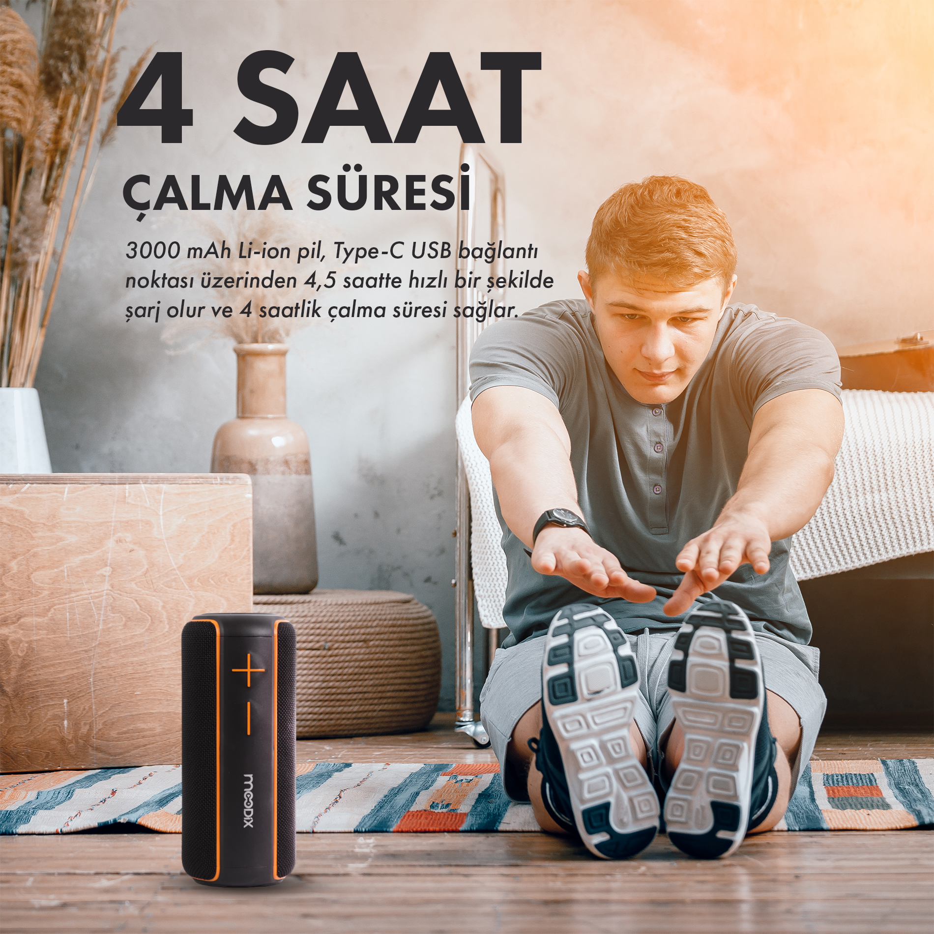 Siyah ve turuncu bir hoparlörün yanında bir adam esniyor. Yukarıdaki metin 4 saat çalma süresi olduğunu belirtiyor.