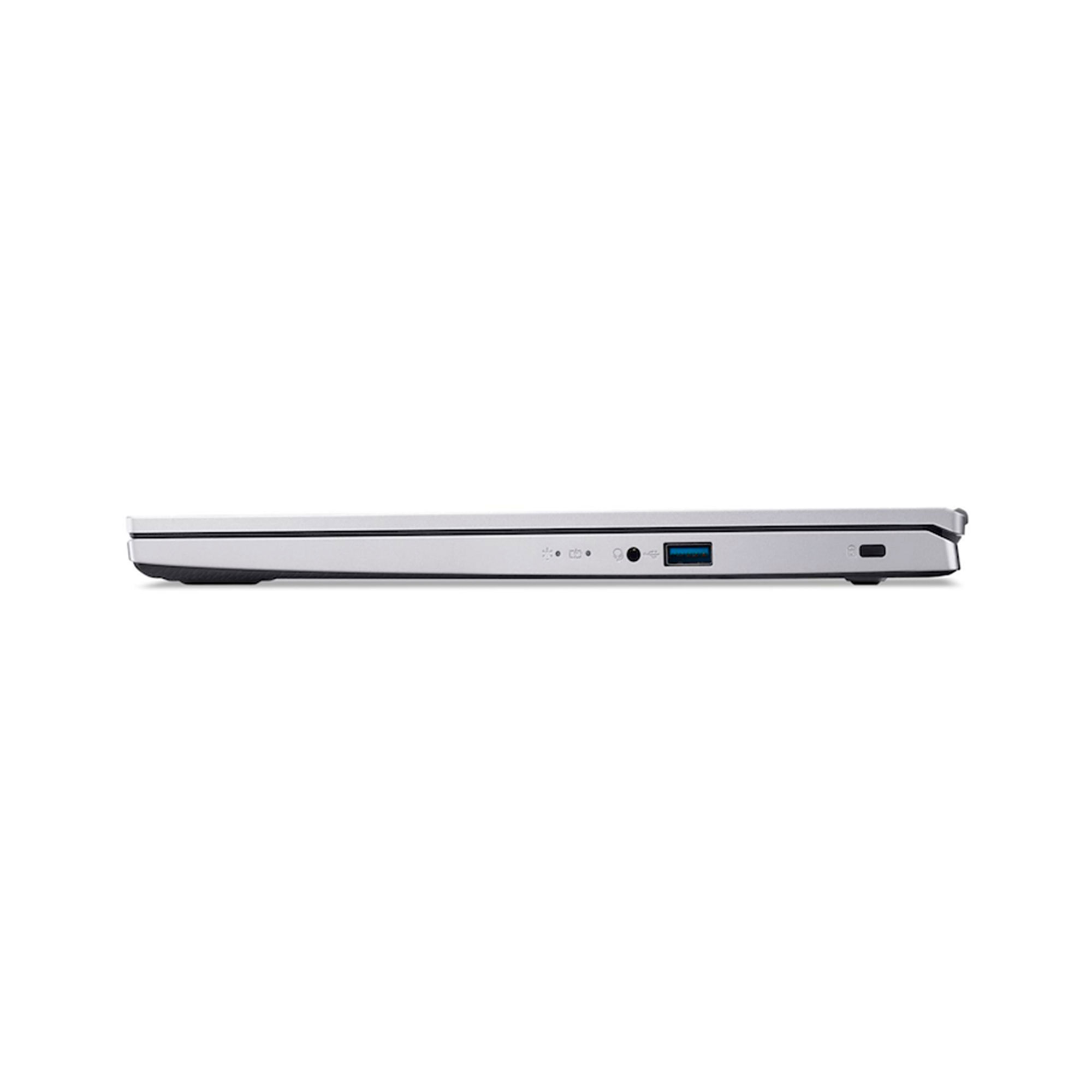 Vista lateral de un portátil plateado. Los puertos visibles incluyen USB, conector de audio y entrada de alimentación. El portátil está sobre un fondo blanco.