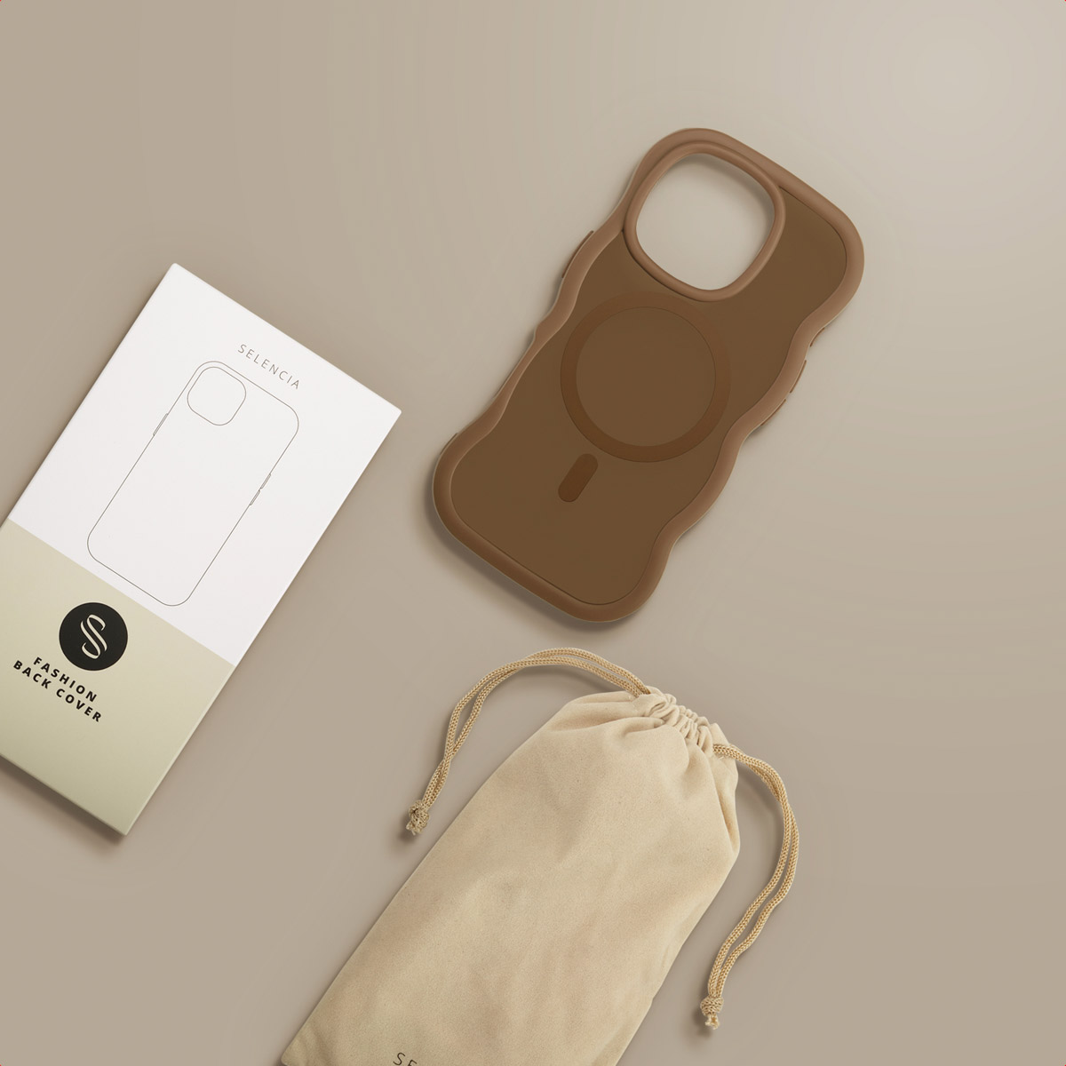 Een bruine telefoonhoes, een witte doos met een telefooncontour en een beige zakje liggen op een lichtbruin oppervlak.