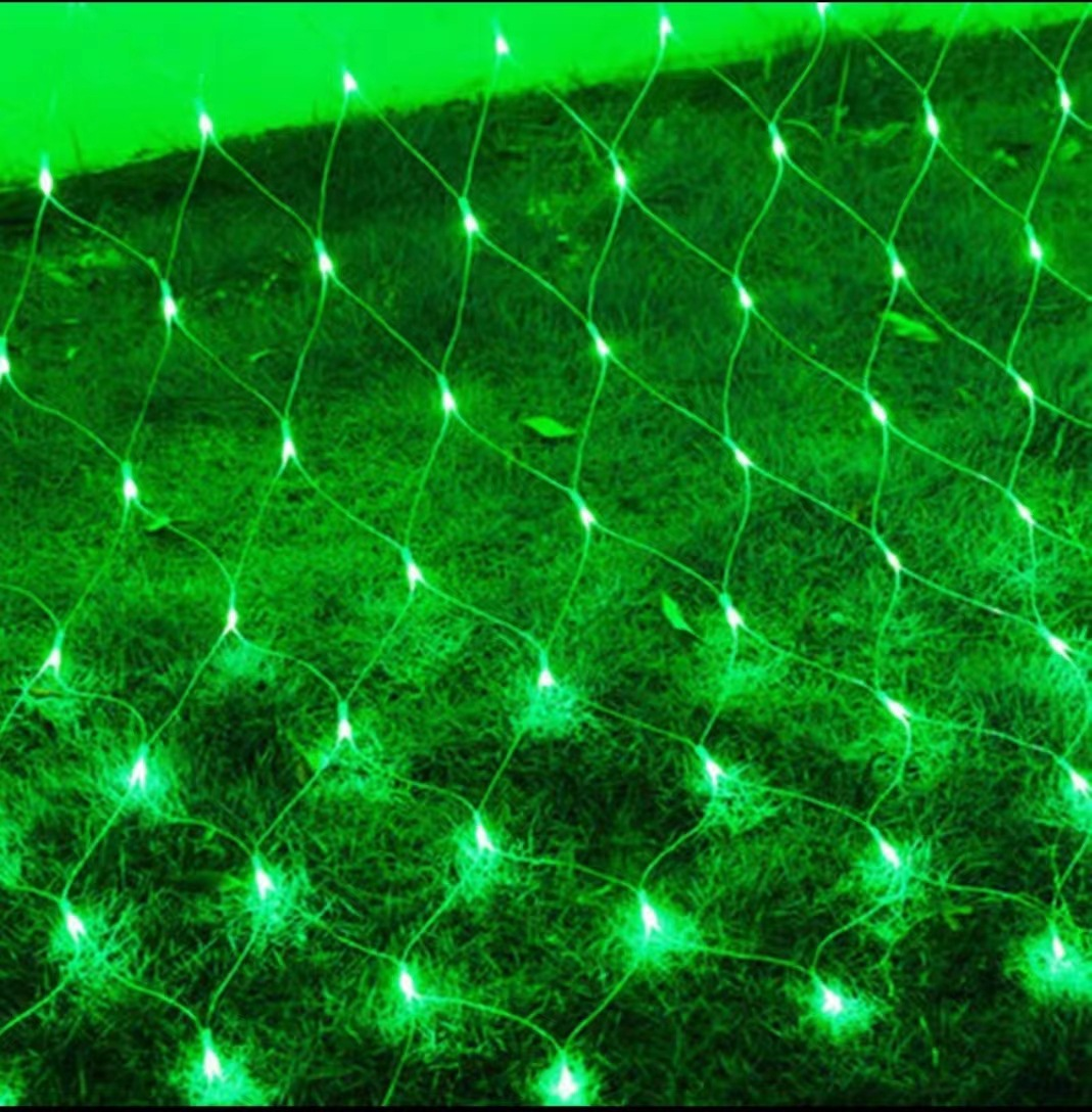 Ein grünes Lichternetz ist über Gras drapiert. Die Lichter sind hell, und das Netz hat ein Gittermuster. Die Szene ist grün beleuchtet.