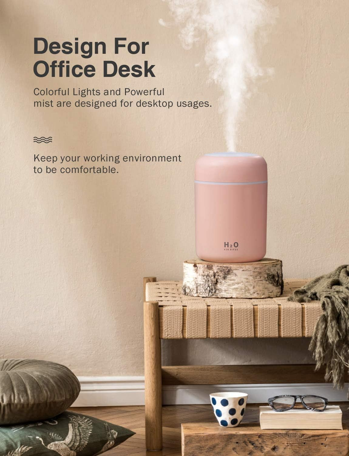 Ein rosa Luftbefeuchter, der Nebel ausstößt, steht auf Holz. Eine Bank mit Decke, Büchern, Brille und Tasse im Vordergrund.