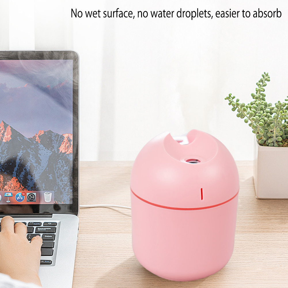 Ein rosa Luftbefeuchter neben einem Laptop. Eine Hand tippt auf der Tastatur. Im Hintergrund eine kleine Pflanze.