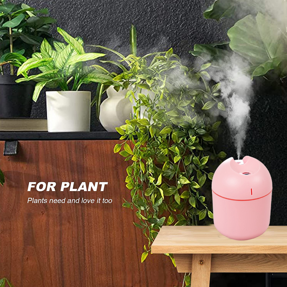 Ein rosa Luftbefeuchter auf einem Holztisch, mit Pflanzen im Hintergrund. Weißer Dampf wird ausgestoßen. Text: FÜR PFLANZEN, Pflanzen brauchen und lieben es auch.