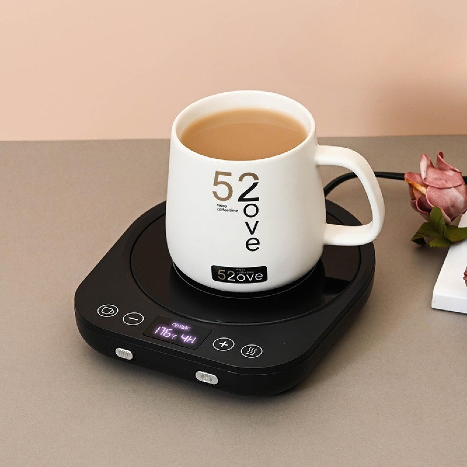 Ein weißer Becher mit Kaffee steht auf einem schwarzen Wärmer. Der Becher hat '52ove' aufgedruckt. Eine Rose ist an der Seite.