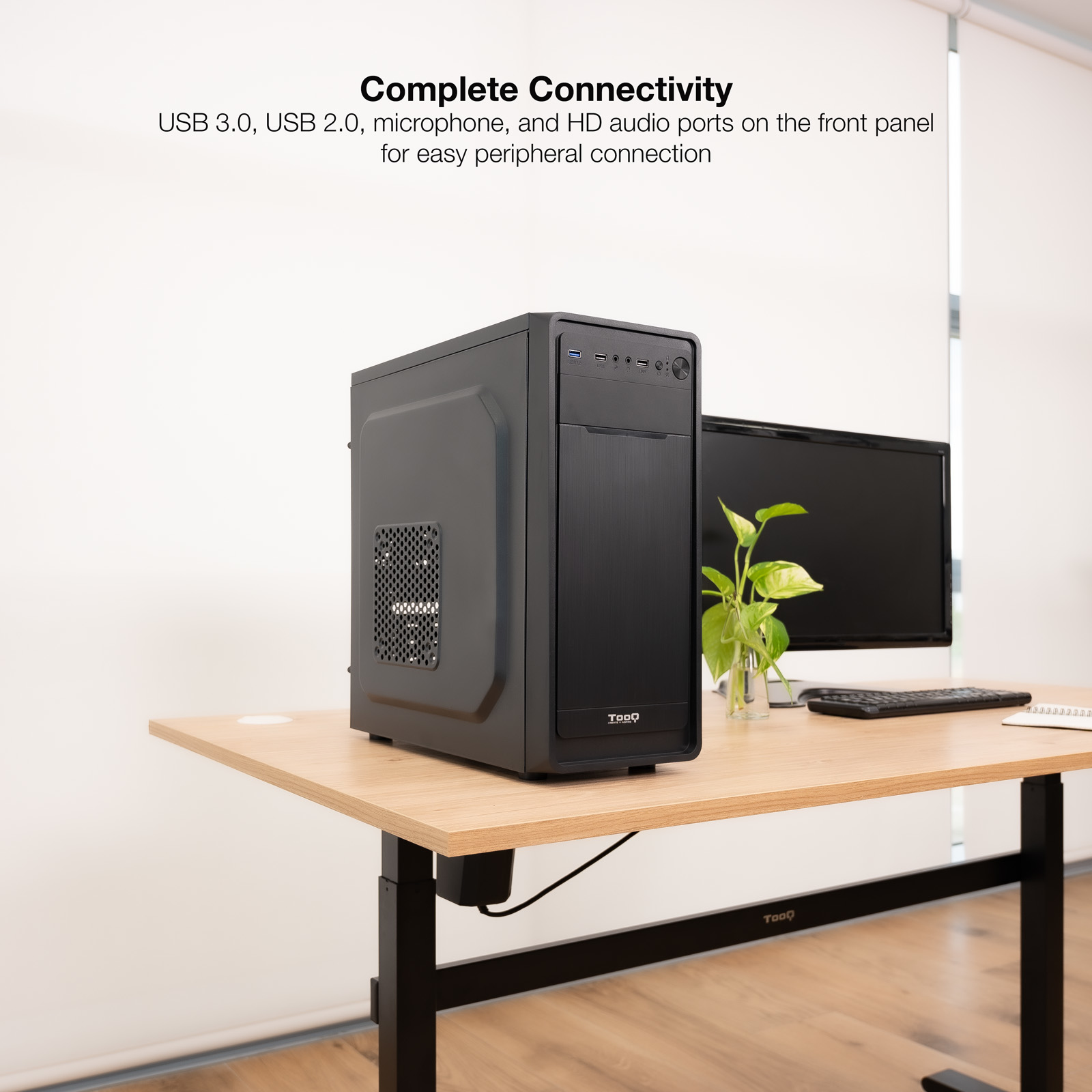 Un case nero per computer su una scrivania di legno. Sono presenti anche un monitor, una tastiera e una pianta.