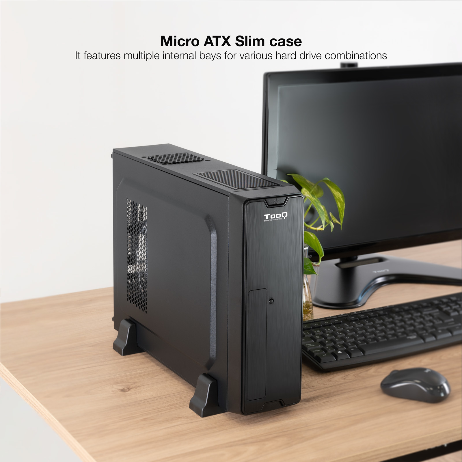 Un case per computer Micro ATX nero su una scrivania di legno, con monitor, tastiera, mouse e una pianta sullo sfondo.