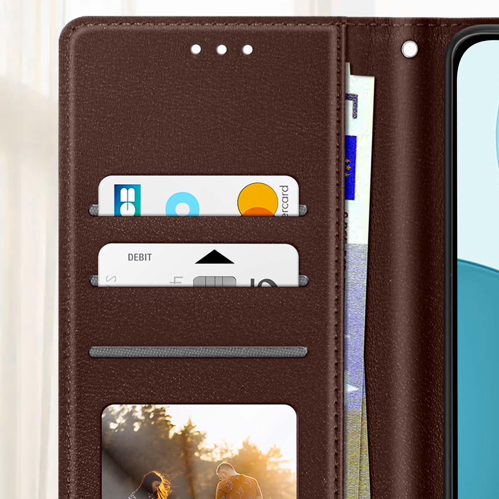 Eine braune Handyhülle mit Kartenfächern. Karten und ein Foto sind sichtbar. Ein Telefon ist teilweise rechts sichtbar.