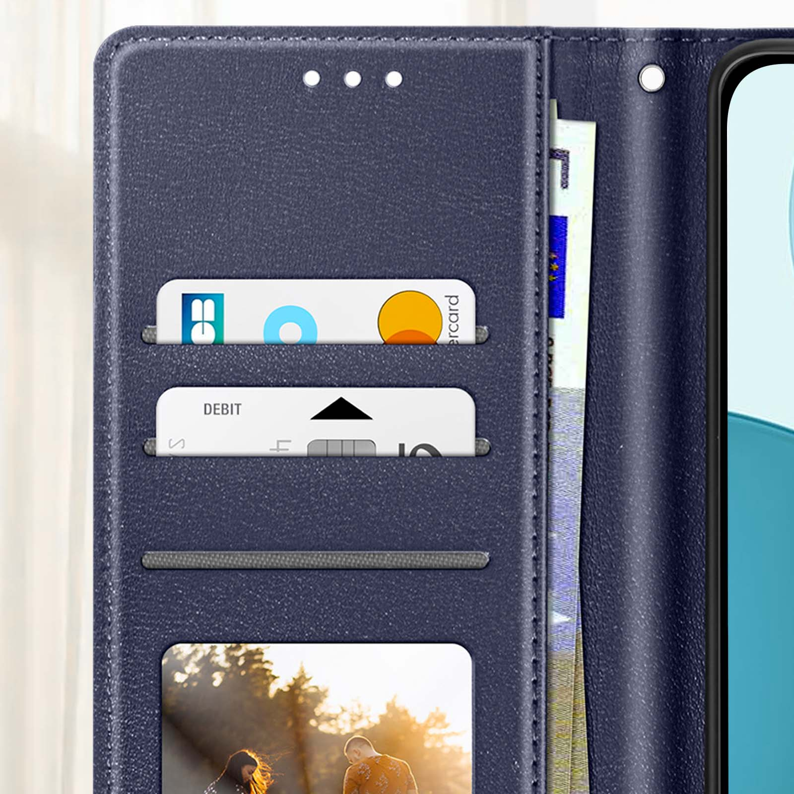 Una custodia a portafoglio blu con carte e un telefono. Le carte includono una Mastercard e una carta di debito. È visibile anche denaro.