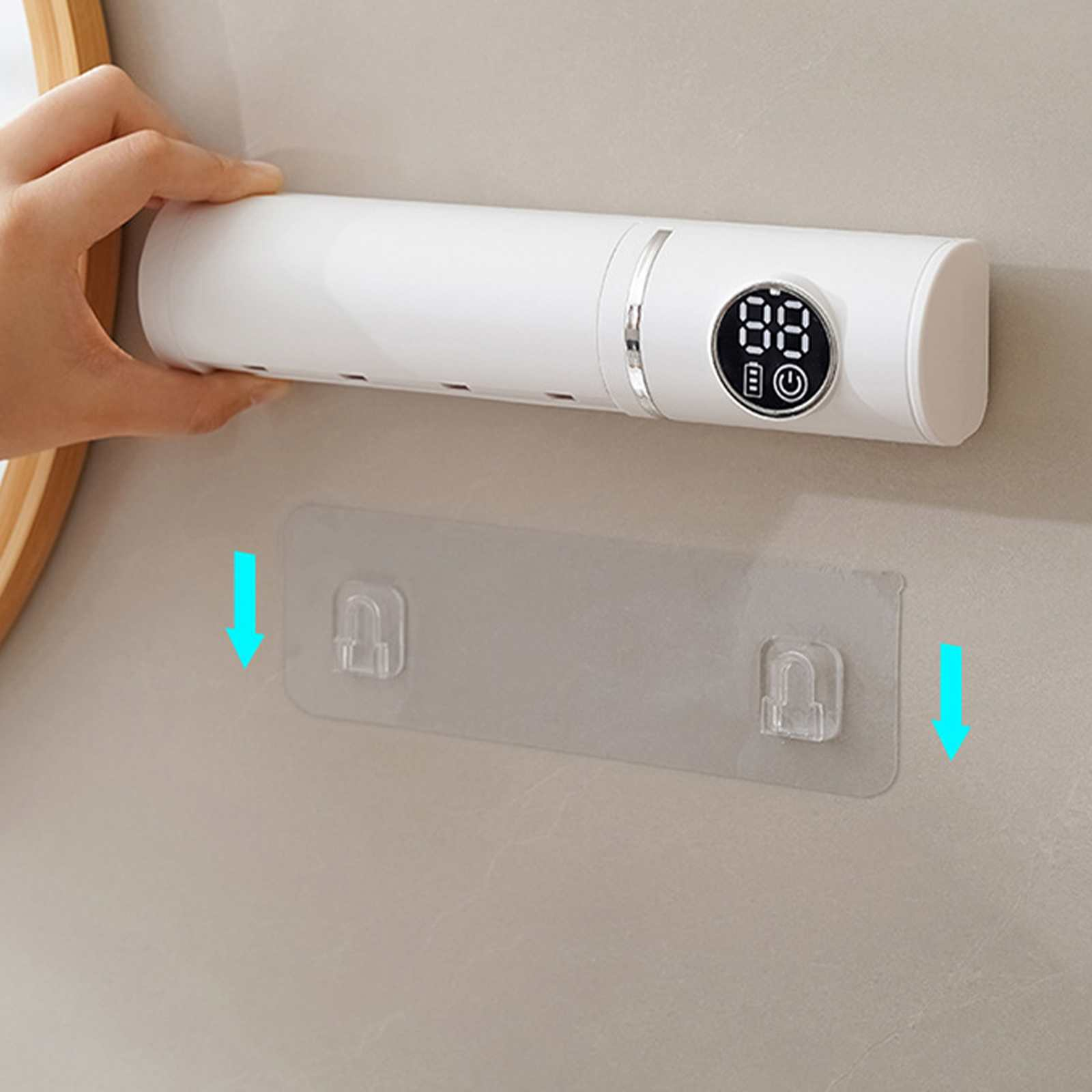 Ein weißes Gerät wird über einem Klebepad an einer Wand gehalten. Digitalanzeige und Pfeil nach unten.