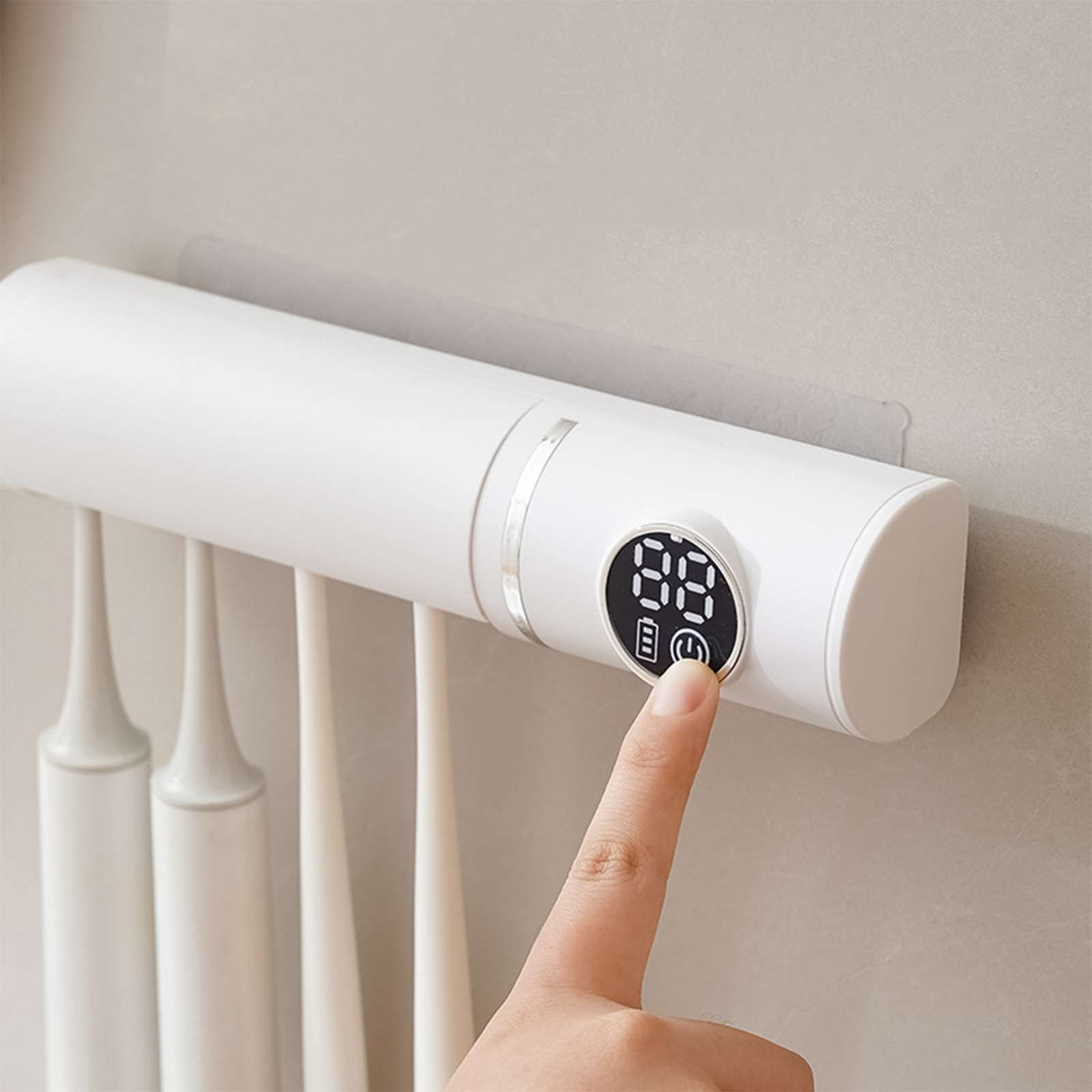 Eine Hand drückt die Power-Taste auf einem weißen Zahnbürsten-Sanitizer. Das Display zeigt Zahlen.