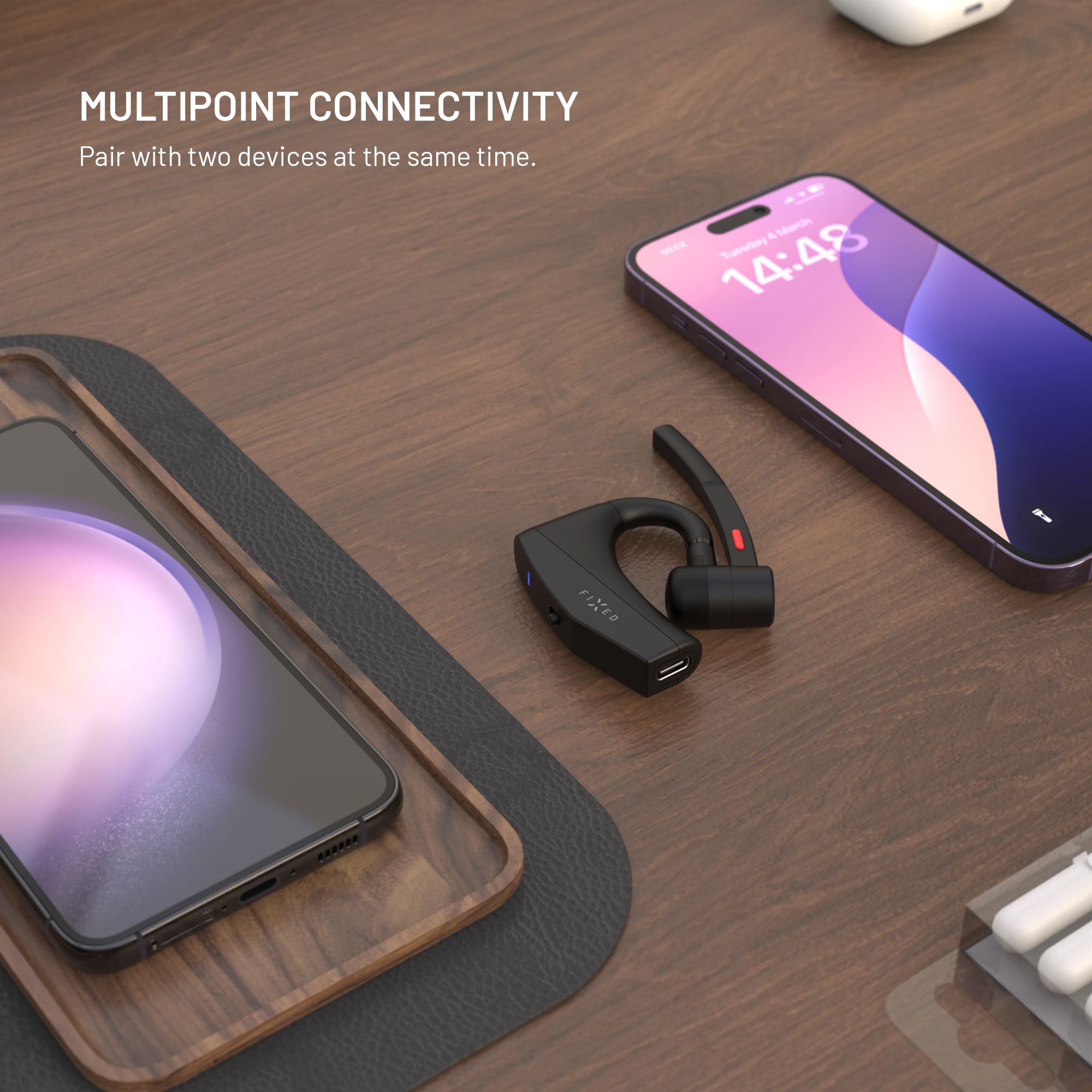 Schwarzes Headset und zwei Telefone auf einem Holztisch. Ein Telefon zeigt die Uhrzeit. Text sagt Multipoint-Konnektivität.