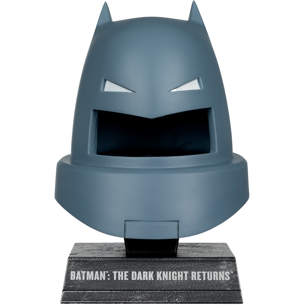 Una statuetta grigia del casco di Batman da 'The Dark Knight Returns' è esposta su una base nera con il titolo stampato.