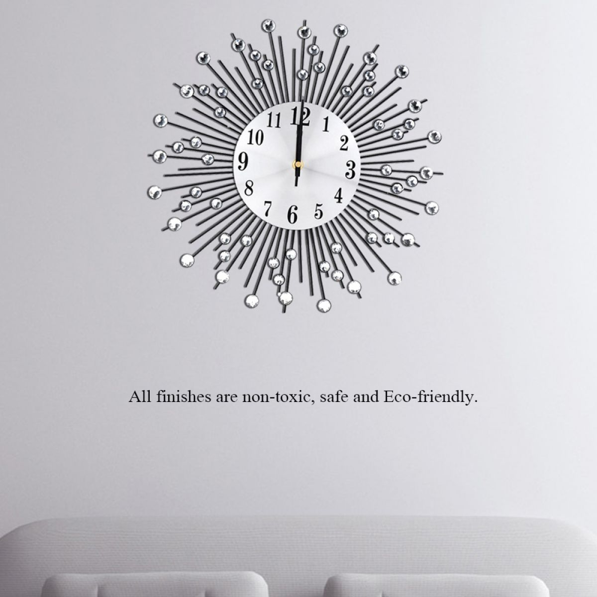 Eine dekorative Wanduhr mit weißem Zifferblatt und schwarzen Zahlen. Sie hat ein Sonnenstrahl-Design mit Kristallakzenten. Darunter befindet sich ein Sofa.